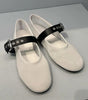 White shoes with black straps on a light gray background