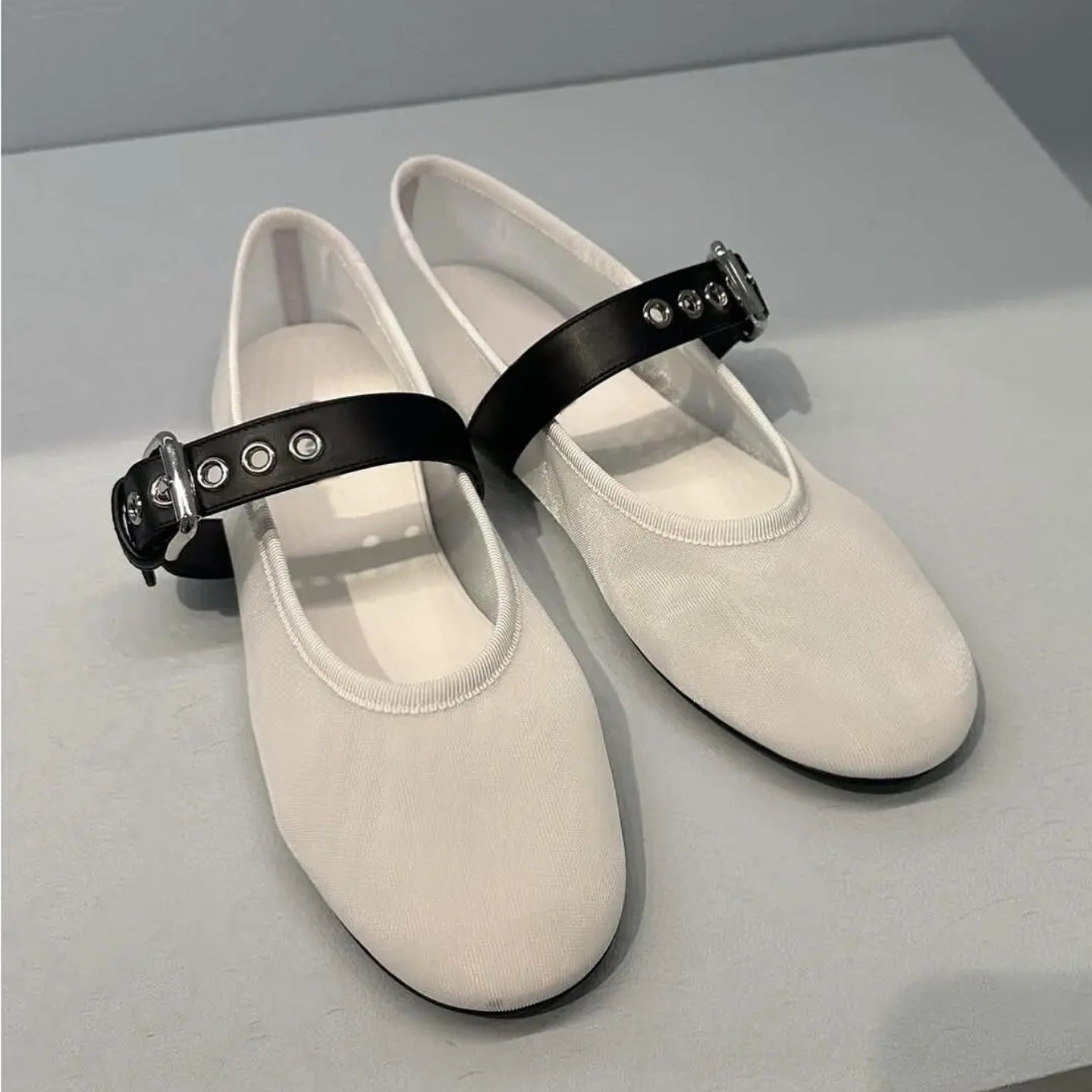 White shoes with black straps on a light gray background